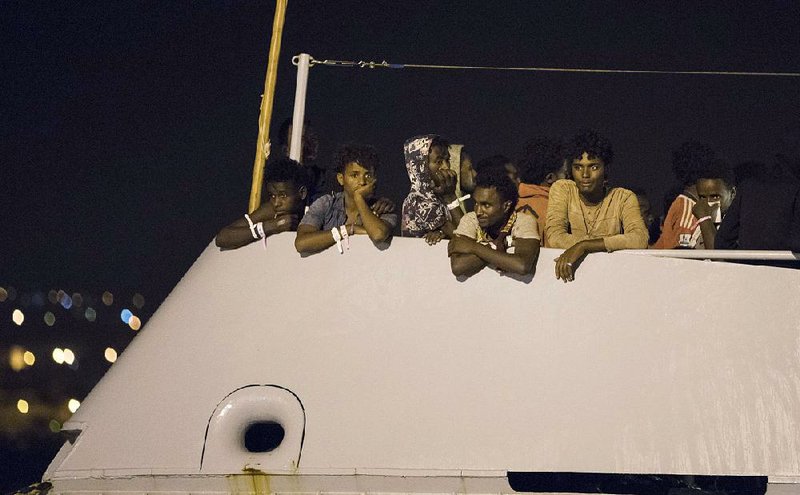 Migrants wait to disembark from Frontex ship Protector at the port of Pozzallo, Sicily, Italy, early Monday.  