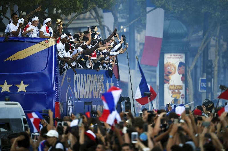 France’s players celebrate on the roof of a bus while parading down the Champs-Elysees Avenue in Paris on Monday after France defeated Croatia 4-2 on Sunday for its first World Cup title in 20 years.  