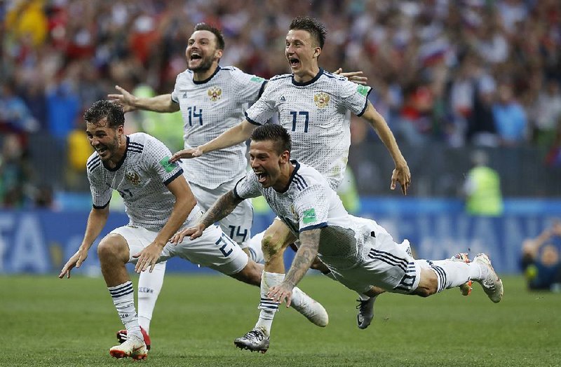 Russia’s Fyodor Smolov (right) dives as he celebrates with teammates after Russia defeated Spain 4-3 on penalty kicks in the round of 16 on July 1. Russia earned high marks for its play on the field and as the host country for the World Cup from many observers.  