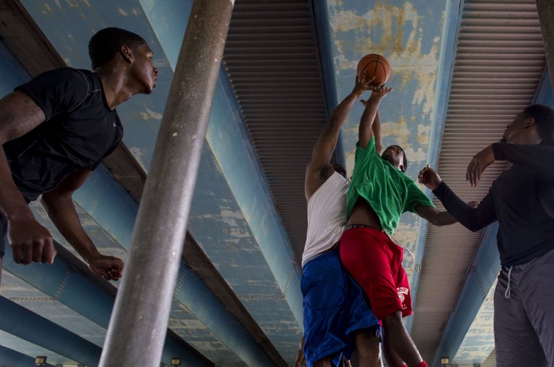 FILE — Left to right, James Freeman, Kevin Cross, Darrius Smith, and Antwione Garner, play a game of half court basketball under the I-630 bridge at Kanis Park July 6, 2014.
