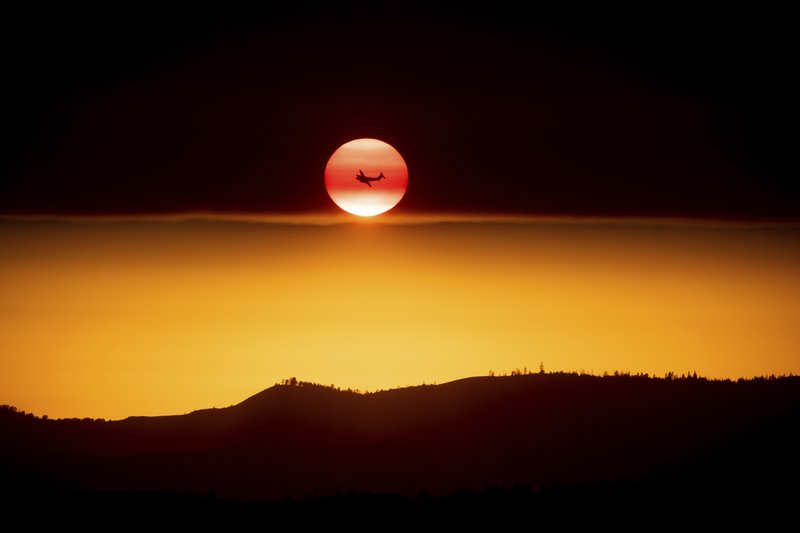 The Associated Press SETTING SUN: A plane battling the Ferguson Fire passes the setting sun in unincorporated Mariposa County Calif., near Yosemite National Park on Sunday.