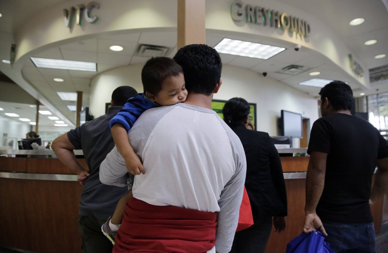 In this June 21, 2018, file photo, a group of immigrants from Honduras and Guatemala seeking asylum stand in line at the bus station after they were processed and released by U.S. Customs and Border Protection in McAllen, Texas. The Trump administration has quietly made it harder for Central Americans fleeing gangs, drug smugglers and domestic violence to travel to the U.S. and ask for asylum.  (AP Photo/Eric Gay, File)