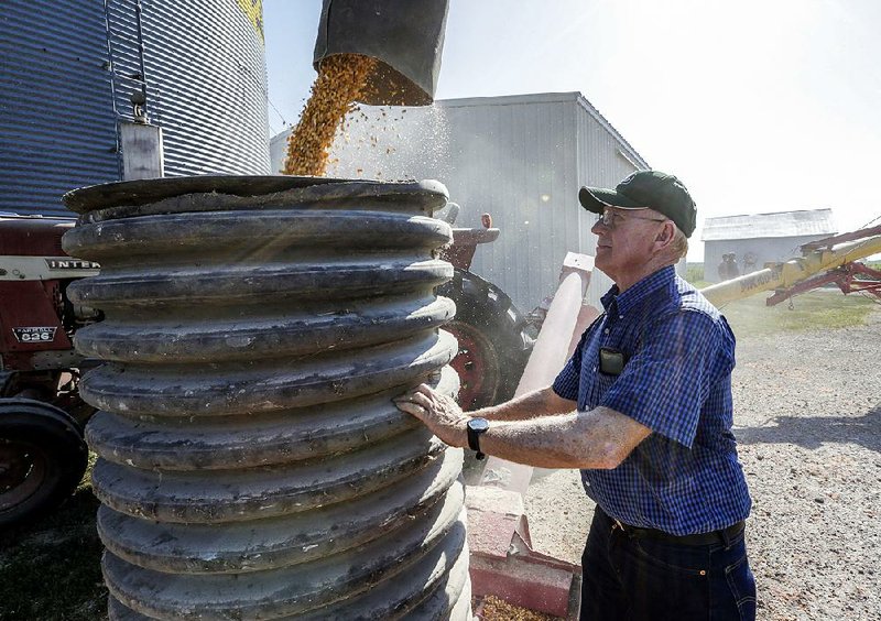Farmer Don Bloss checks on the operation of an auger transferring corn on his farm in Pawnee City, Neb. Farmers helped elect President Donald Trump and are worried about the costs of his trade policies, but many are standing by him for now. 