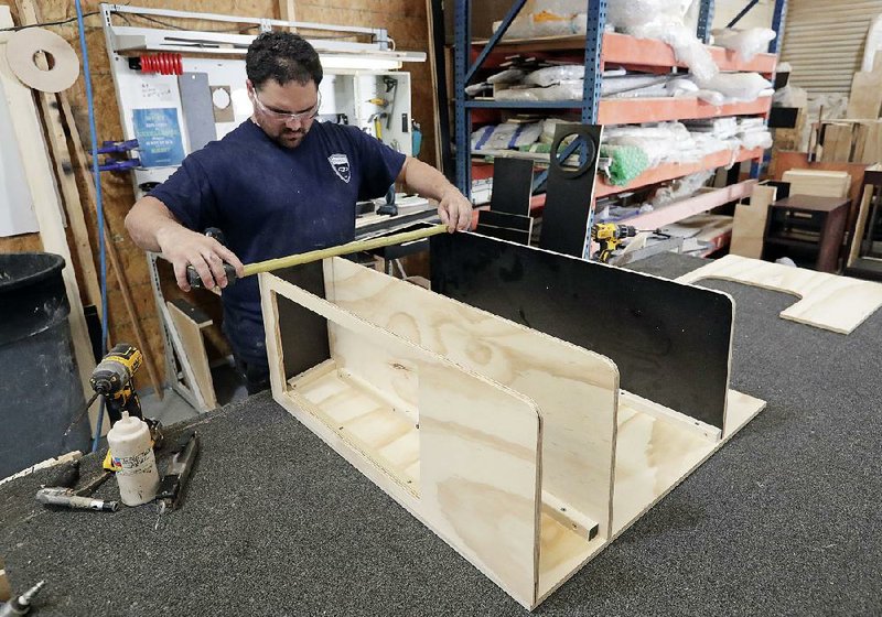 A worker assembles interior cabinets for a boat recently at Regal Marine Industries in Orlando, Fla. U.S. factory production rebounded in June after a fi re-related disruption at an auto parts supplier caused a slump in May. 