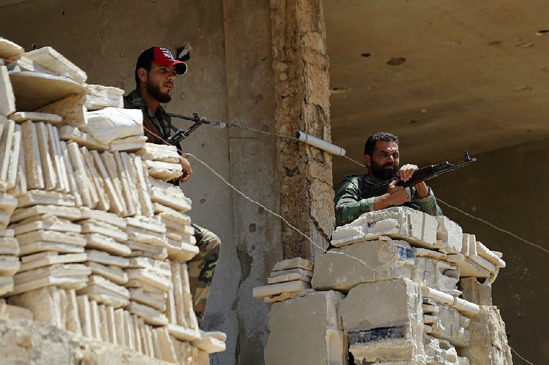 Soldiers stand guard Tuesday at their post overlooking a highway in Rastan, a town in central Syria’s Homs province. Government forces have turned their attention to areas near the frontier with Israel after clearing rebels from other parts of the country.   