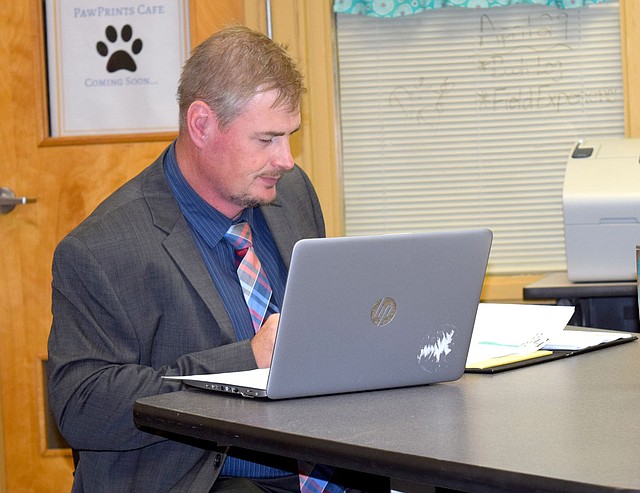 Westside Eagle Observer/MIKE ECKELS Steve Watkins reviews a few notes before the July 9 school board meeting in the library at Decatur High School. This meeting marked Watkins' first as the new Decatur superintendent after taking over the position from Jeff Gravette June 26.