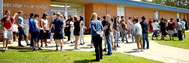 Westside Eagle Observer/MIKE ECKELS Several Decatur High School students mill around the main entrance to the high school Aug. 21, 2017, after viewing a solar eclipse. Students will walk through the doors at Decatur High School for the 2018-19 school year which begins Aug. 13.
