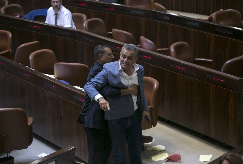 A Knesset usher removes Jamal Zahalka, an Israeli Arab member of the Knesset representing the Balad party, who was protesting the passage of a contentious bill, during a Knesset session in Jerusalem, Thursday, July 19, 2018. (AP Photo/Olivier Fitoussi)

