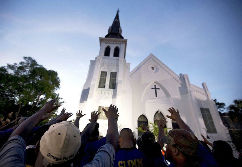 In this June 19, 2015 , file photo, the men of Omega Psi Phi Fraternity Inc. lead a crowd of people in prayer outside Emanuel African Methodist Episcopal Church, after a memorial service for the nine people killed by Dylann Roof in Charleston, S.C.  