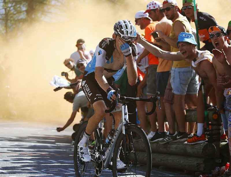 France’s Romain Bardet (shown) covers his eyes after passing through smoke from flares lit by fans along the route during the climb up Alpe d’Huez during Thursday’s 12th stage of the Tour de France. 