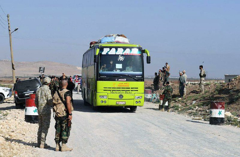 Syrian troops at the Tel el-Eis crossing between Aleppo and Idlib provinces in Syria oversee Thursday’s evacuation of people from the two pro-government villages of Foua and Kfraya.  