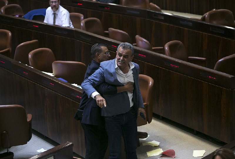 Jamal Zahalka, an Israeli Arab member of the Knesset, is removed from the chamber in Jerusalem as he protests Thursday’s passage of a bill declaring Israel the Jewish state.  
