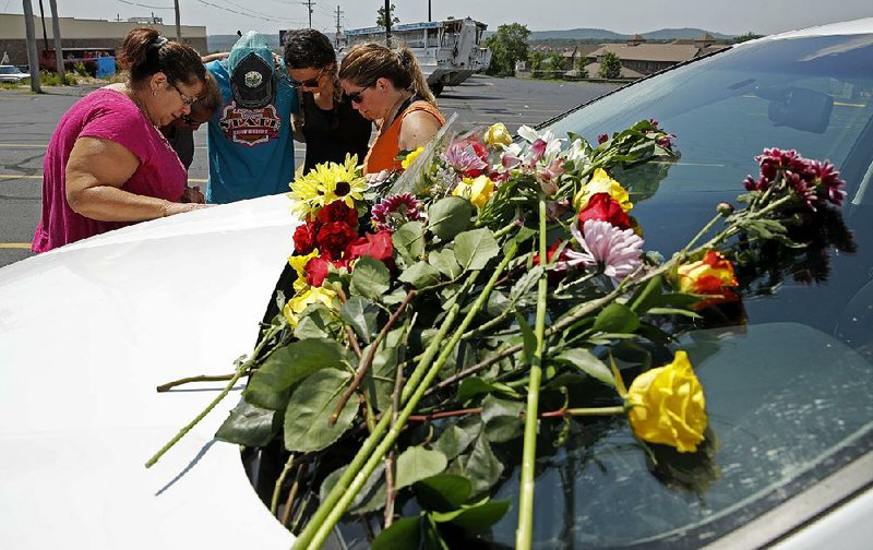 People pray next to a car believed to belong to a victim of Thursday night’s boating accident on Table Rock Lake in Branson. 