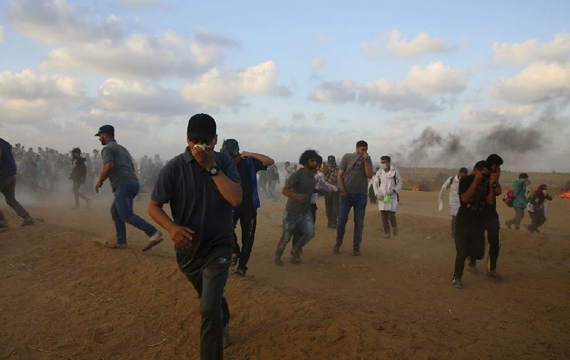 Protesters run from tear gas fired Friday by Israeli troops near the Gaza Strip border with Israel.  