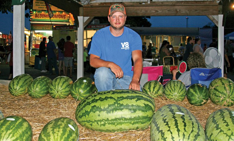 Kolton Moore kneels behind his Best of Show watermelon that weighed in at 107 pounds during the 2016 Cave City Watermelon Festival. Moore planted and tended the prize-winning melon with his father, Kevin Moore, of Moore Farms in Cave City.
