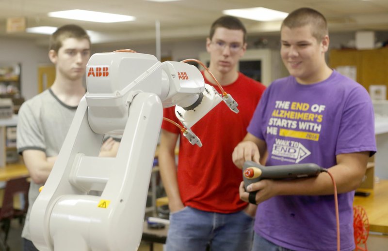 NWA Democrat-Gazette/DAVID GOTTSCHALK Jayden Daman (from left), 15, and Avery Francis, 15, watch Andrew Francis, 14, use the teach pendant Friday to control an industrial robot ABB 120 in the Electronics Lab at Northwest Technical Institute in Springdale. The University of Arkansas' Global Campus, in partnership with NTI, put on a five-day Explore Skilled Trades camp this week for teens to learn about careers in truck driving, electronics, auto and diesel repair, welding and HVAC.