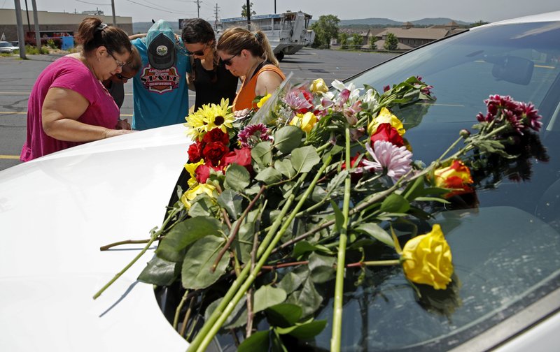 People pray next to a car believed to belong to a victim of a last night's duck boat accident, Friday, July 20, 2018 in Branson, Mo. The country-and-western tourist town of Branson, Missouri, mourned Friday for more than a dozen sightseers who were killed when a duck boat capsized and sank in stormy weather in the deadliest such accident in almost two decades. (AP Photo/Charlie Riedel)