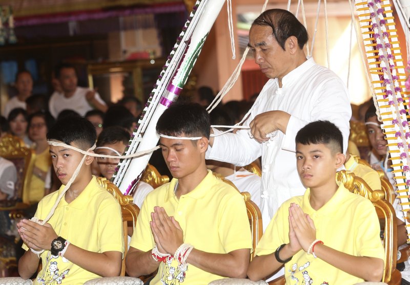 Soccer coach Ekkapol Janthawong, center, and members of the rescued soccer team attend a Buddhist ceremony that is believed to extend the lives of its attendees as well as ridding them of dangers and misfortunes in Mae Sai district, Chiang Rai province, northern Thailand, Thursday, July 19, 2018. The 12 boys and their soccer coach rescued from a cave in northern Thailand left the hospital where they had been recuperating and appeared at a news conference Wednesday, saying the ordeal made them stronger and taught them not to live carelessly. (AP Photo/Sakchai Lalit)