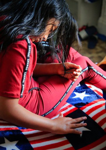 Manuela Adriana, 11, left, use her finger outline a stars and stripes bed cover in her apartment hours after her release from U.S. immigration detention, Wednesday July 18, 2018, in Brooklyn borough of New York. Manuela was separated from her father Manuel Tzah on May 15 after they crossed the U.S. border in Texas from Guatemala, seeking asylum. (AP Photo/Bebeto Matthews)
