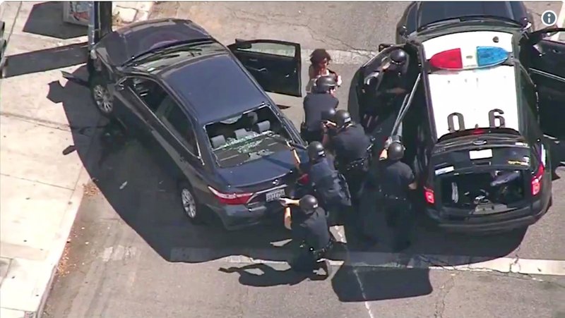 In this image from video provided by KNBC-TV, Los Angeles Police officers remove a passenger from a car that crashed after a pursuit with the driver who ran into a nearby Trader Joe's supermarket in the Silver Lake district of Los Angeles Saturday, July 21, 2018. (KNBC-TV via AP)

