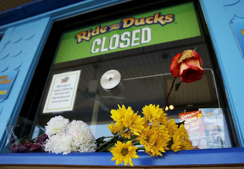 Flowers left by mourners sit at the ticket booth of the closed Ride the Ducks attraction Saturday in Branson.   