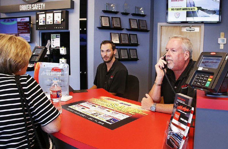 Earlier this month, Greg Goodman (right) assists a customer on the phone while son Chandler Goodman helps a customer at the counter in their Alta Mere franchise in Oklahoma City. 