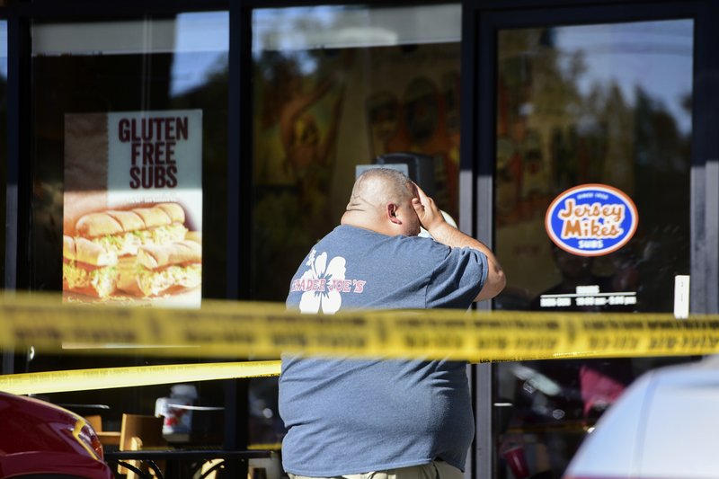In this photo provided by Christian Monterrosa, a Trader Joe's employee is distraught as he recounts his experience just outside the Trader Joe's supermarket where a man held dozens of people hostage before surrendering to police, Saturday, July 21, 2018, in Los Angeles. (Christian Monterrosa via AP)
