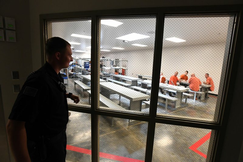 Deputy Chance Gregory looks in on prisoners May 2 at the Benton County Jail in Bentonville. The jail will no longer offer free, in-person visits between inmates and their family and friends starting in September, according to the Sheriff's Office.