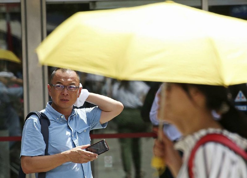 A man wipes sweat Monday in the scorching heat at a business district in Tokyo. Kumagaya, a city about 40 miles northwest of Tokyo, recorded a high temperature Monday of 106 degrees, the hottest reading on record in Japan. A low of 84.6 in Seoul was the highest low ever recorded in the South Korean capital. 