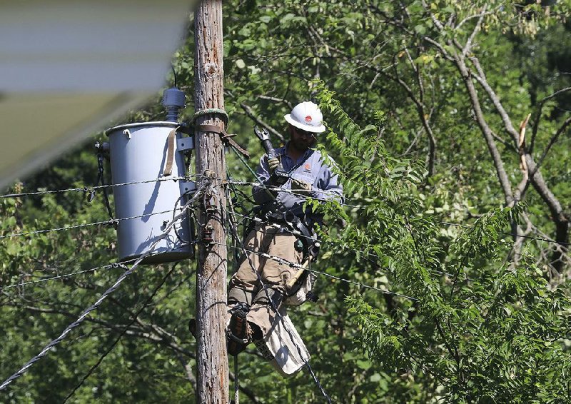 An Entergy lineman works Monday morning on power lines on Greenway Drive in Little Rock after storms on Saturday morning downed trees and power lines in the area. 