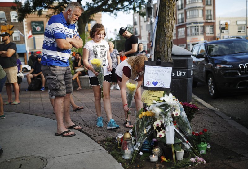 People add flowers and messages to a memorial remembering the victims of Sunday's shooting in Toronto on Monday, July 23, 2018. A man whose family said he suffered from psychosis and depression fired a handgun into restaurants and cafes in a lively Toronto neighborhood, killing a 10-year-old girl and an 18-year-old woman and wounding over a dozen others in an attack that has shaken the confidence of many in the normally safe city. (Mark Blinch/The Canadian Press via AP)