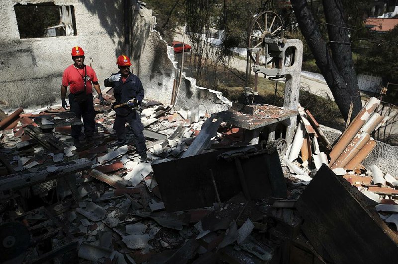 Members of a rescue team search a burned house Wednesday in Mati, Greece, part of an area around Athens where wildfires spread rapidly this week, fanned by gale-force winds.  