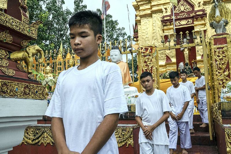 Members of the Wild Boars soccer team and their coach walk in a line as they prepare to become monks at Wat Pha That Doi Wao temple in Mae Sai, Thai- land, on Tuesday. Three weeks after emerging from a flooded cave complex, the group began a ceremony on Tuesday to become novice Buddhist monks.