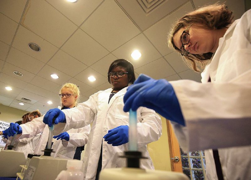 Allie Goertzen (from left), 12, Madison Caldwell, 13, and Madeline Fithen, 12, mix samples in test tubes Thursday as they learn about forensic chemistry during the Girls in STEM workshop at the Museum of Discovery in Little Rock. 