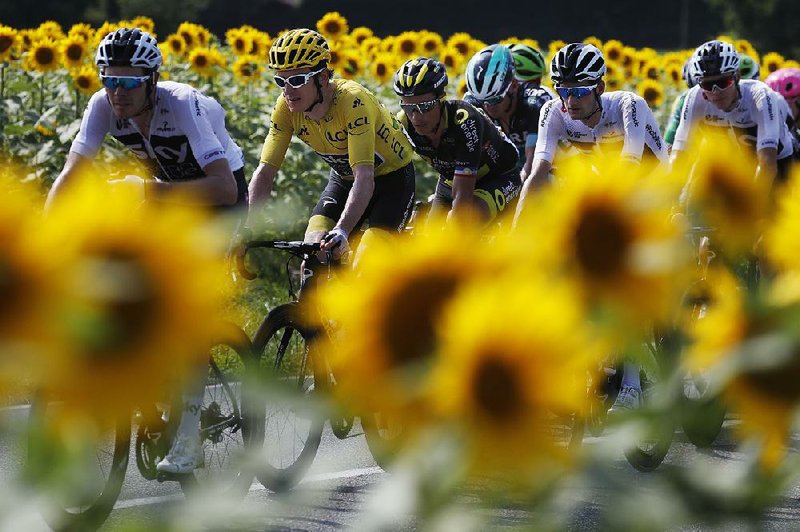 Overall leader Geraint Thomas (yellow jersey) and other riders pedal past a field of sunflowers during Thursday’s 18th stage of the Tour de France. 