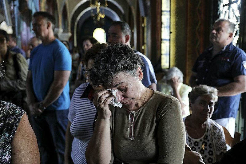 Orthodox faithful attend a service Sunday in a church at Mati, Greece, for the forest fire victims.