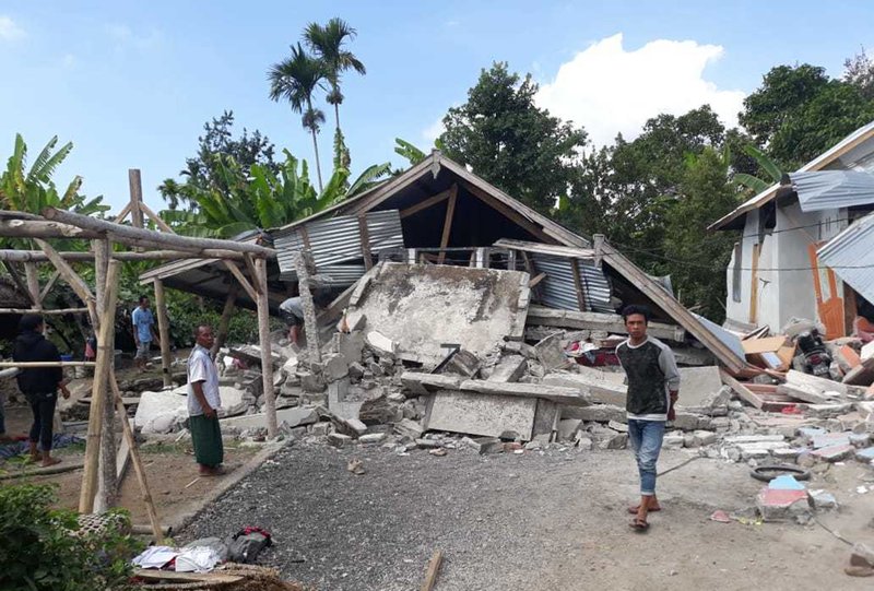 Villagers walk near destroyed homes in an area affected by a strong earthquake at Sajang village, Sembalun, East Lombok, Indonesia, early Sunday.