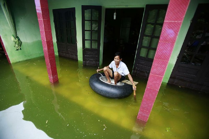 Nguyen Van Bon paddles in a rubber tire Tuesday at his flooded house in the Chuong My district, a suburb of Hanoi, Vietnam.
