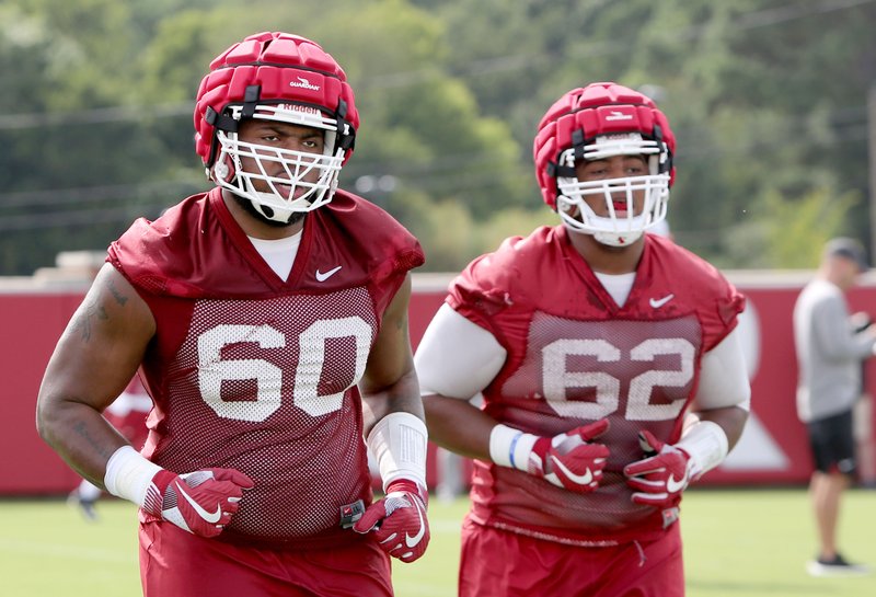 NWA Democrat-Gazette/David Gottschalk BIG LOSERS: Arkansas Razorbacks offensive linemen Brian Wallace (60) and Johnny Gibson (62) prepare for practice on campus in Fayetteville on July 17, 2017. The two are among the linemen anchoring the offensive line after Colton Jackson's injury.