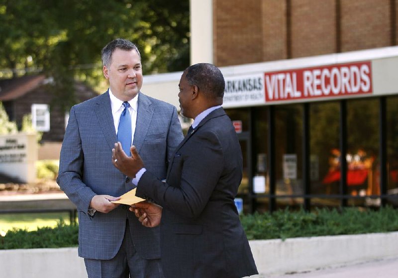 Shane Carter (left) gets his birth records Wednesday from Nathaniel Noble, branch chief for vital records for the Arkansas Health Department, outside the Health Department in Little Rock.