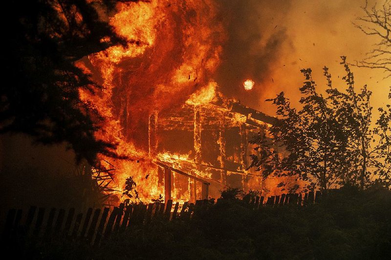 Flames from a wildfire consume a home Tuesday in Lakeport, Calif.