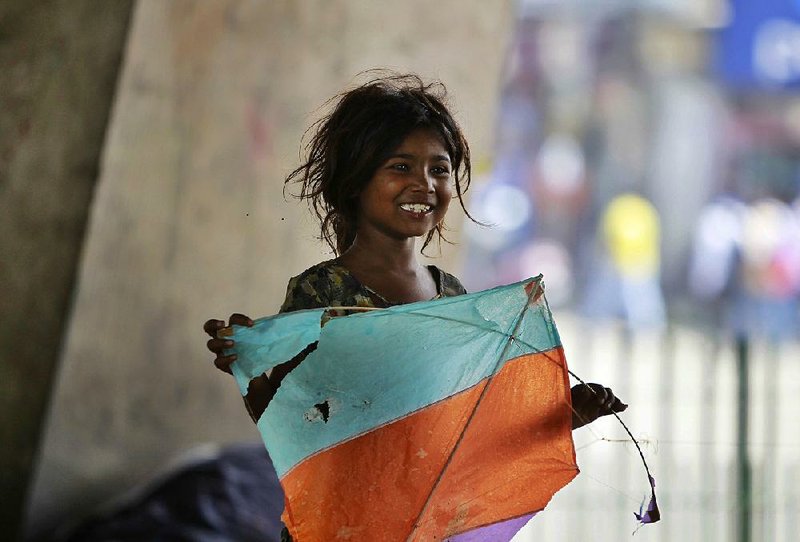 An Indian girl who lives under an overpass plays with a kite Thursday in Jammu. Hundreds of millions of people in India survive on less than $2 a day.