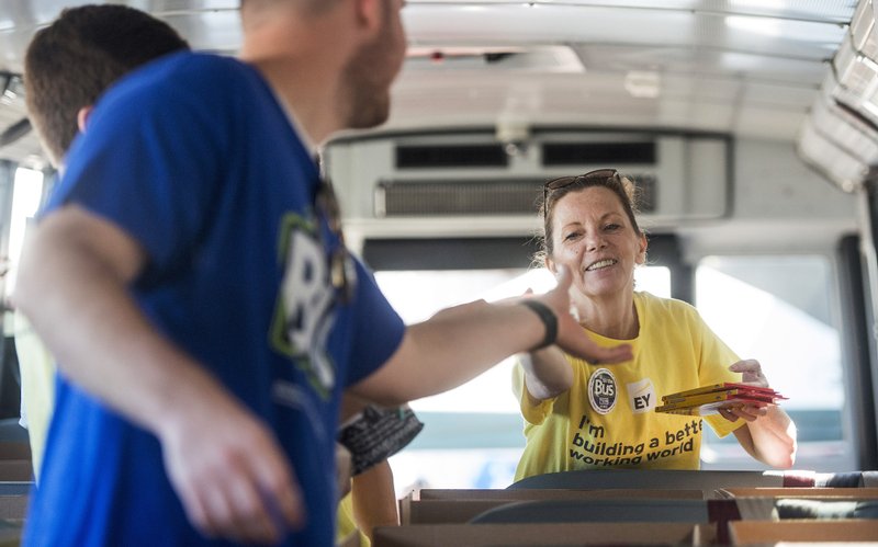 NWA Democrat-Gazette/BEN GOFF &#8226; @NWABENGOFF Donna Prince hands supplies Friday to Johnathan Loessel while volunteering with other employees from Ernst &amp; Young in Rogers to help with the United Way of Northwest Arkansas' Fill the Bus campaign at the Walmart on Pleasant Crossing Boulevard in Rogers. Volunteers are manning busses at 10 Walmart locations in Northwest Arkansas and Pineville, Mo., from 9 a.m. to 3:30 p.m. today to sort donated school supplies. The donations will go to the school district the Walmart location is in. Over the past 10 years, the annual drive has helped more than 35,000 students in 12 school districts get the supplies they need to start the school year.