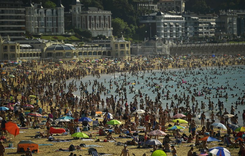 People crowd La Concha beach in the basque city of San Sebastian, northern Spain, Friday, Aug. 3, 2018. Hot air from Africa is bringing a heat wave to Europe, prompting health warnings about Sahara Desert dust and exceptionally high temperatures that could peak at 47 degrees Celsius (117 Fahrenheit) in Spain and Portugal. (AP Photo/Alvaro Barrientos)