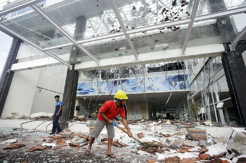 A worker cleans up at a damaged building today in Bali, Indonesia, after the second strong earthquake in a week struck the nearby resort island of Lombok.