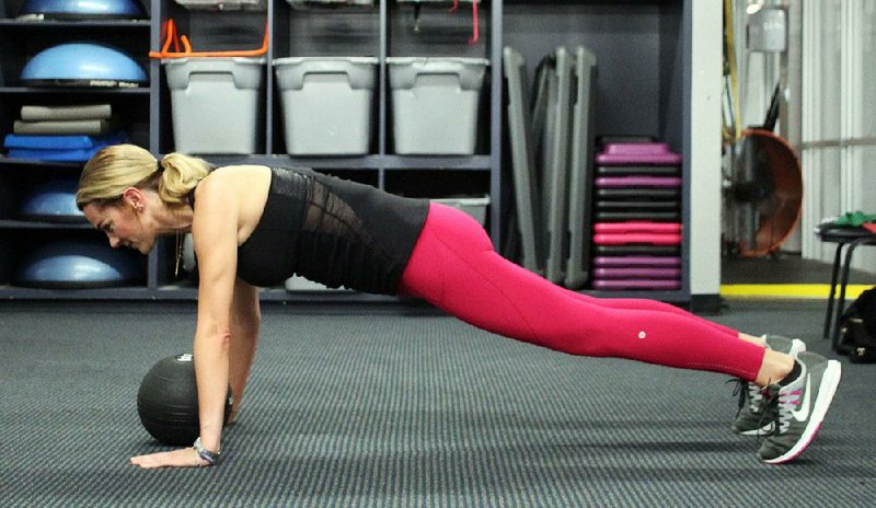 Ashley Bermingham does the Medicine Ball Up Down, which adds a balance and hold to the routine pushup, increasing the difficulty dramatically. Steps 1 and 3.