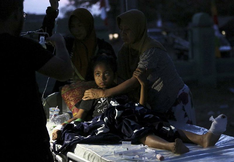 A doctor examines a child Tuesday at a makeshift hospital after she was injured in Sunday’s earthquake.  