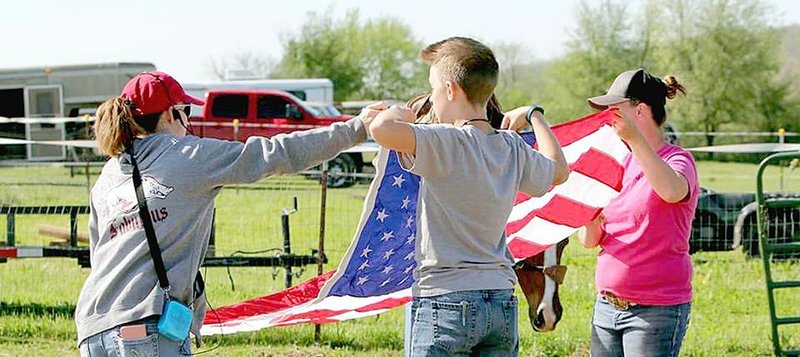 Submitted photo Members of Lincoln Riding Club's precision drill team known as 'The Regulators' and participants in an April 29 clinic conducted by the team fold an American flag. 'The Regulators' proudly carry the U.S. and other flags on horseback during rodeo performances.