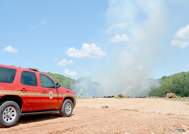 Keith Bryant/The Weekly Vista A fire department vehicle sits nearby as a column of smoke rises from the former stump dump off Trafalgar Road.