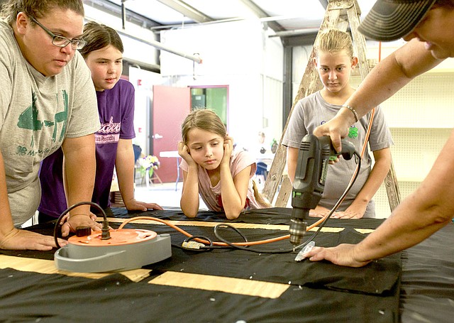 NWA Democrat-Gazette/CHARLIE KAIJO Shannon Brown of Maysville (right) drills as Tonya Farrister, Kelli McGarrah, 10, Kinzie McGarrah, 7 and Laney Brown, 13, from the Maysville 4-H Club (from left) watch, Saturday, August 4, 2018 at the Benton County Fairgrounds in Bentonville. Vendors prepared their booths ahead of the Benton County Fair which is set to begin August 7.